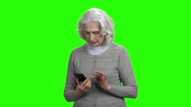 Yeşil ekranda akıllı telefon ile gülümseyen yaşlı kadın.