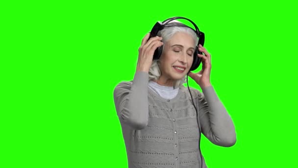 Schöne Seniorin hört Musik über Kopfhörer. — Stockvideo