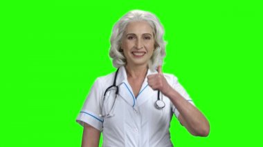 Kıdemli kadın doktor baş parmağını gösteriyor..