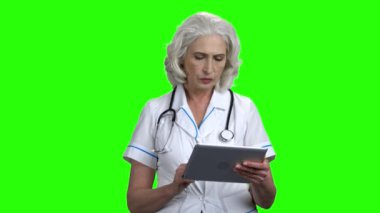 Yeşil ekranda tablet pc ile ciddi doktor.