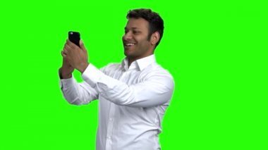 Gülümseyen genç adam cep telefonuyla selfie çekiyor..