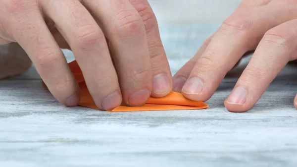 Крупним планом чоловічі руки складаний помаранчевий папір . — стокове фото