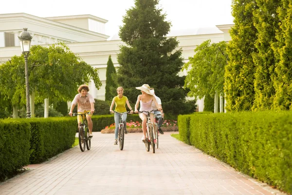 Gelukkige studenten rijden fietsen in het zomerpark. — Stockfoto