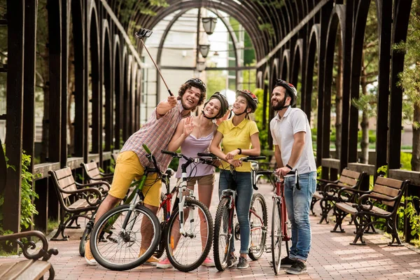 Group of joyful cyclists taking selfie outdoors.