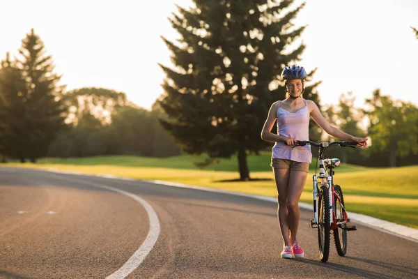 Ung leende kvinna med cykel på vägen. — Stockfoto