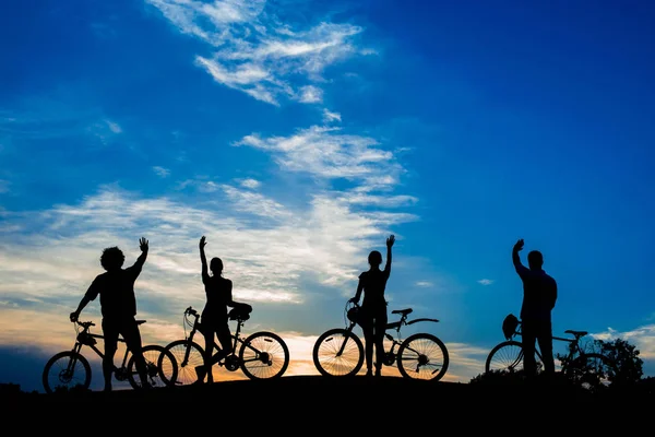 Cyclistes agitant les mains sur le coucher du soleil du soir . — Photo