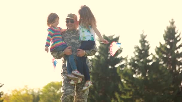 Żołnierz chodzenie trzyma dwa urocze dziewczynki w parku. — Wideo stockowe