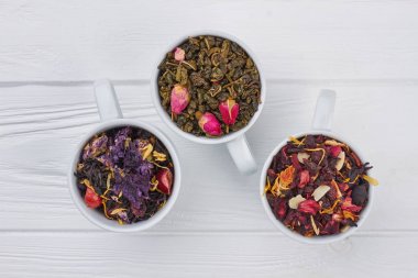 Ahşap arka plan üzerinde çeşitli çay ile üç bardak.