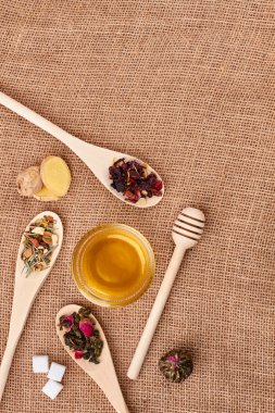 Çuval bezi üzerinde çay yaprakları ve bal, üst görünümü.