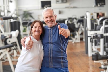 Spor salonunda başparmak veren yaşlı çift.