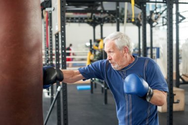 Spor salonunda boks yapan yaşlı erkek kişi.