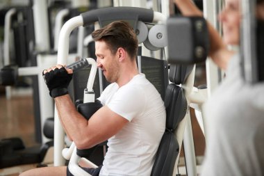 Spor salonunda yakışıklı kaslı adam egzersizleri yapıyor.