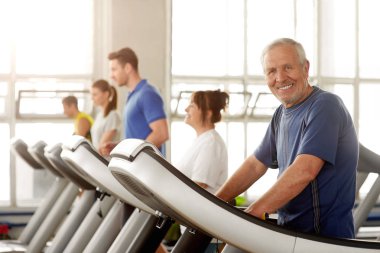 Gülümseyen yaşlı adam spor salonunda egzersiz.