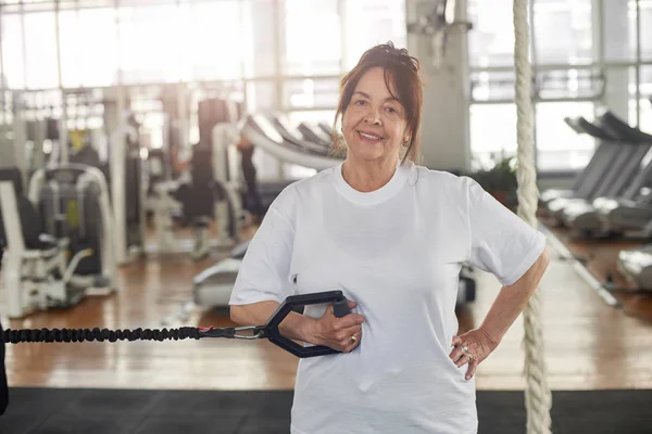 Happy senior woman in gym doing suspension training. — Stock Photo, Image