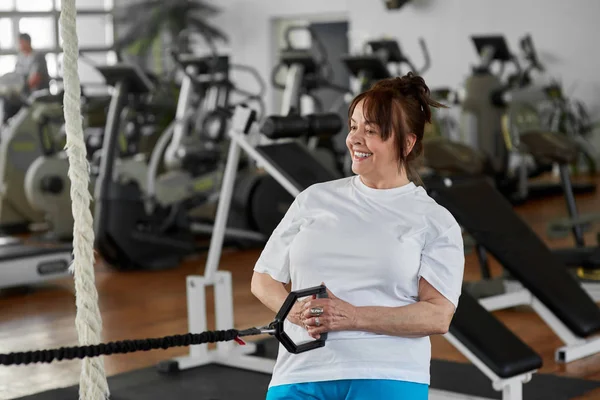 Older woman exercises in modern gym. — Stock Photo, Image