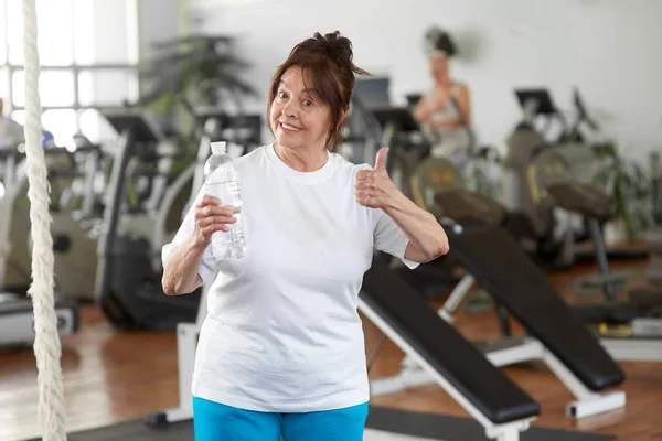Active woman giving thumb up in gym. — Stock Photo, Image