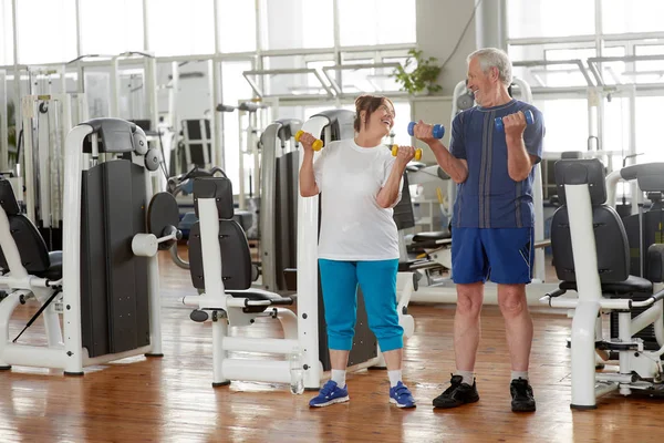 Feliz pareja de ancianos levantando pesas en el gimnasio. — Foto de Stock