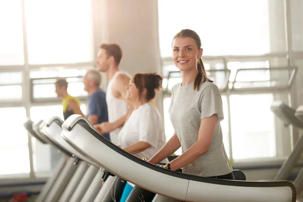 Fit mujer corriendo en la cinta sonriendo a la cámara . — Foto de Stock