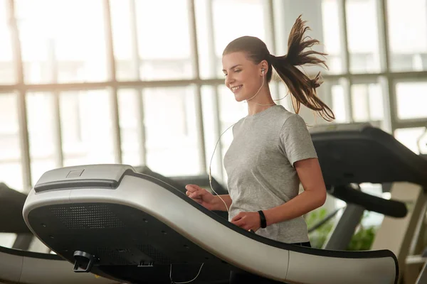 Chica alegre en erófonos corriendo en la cinta de correr . — Foto de Stock