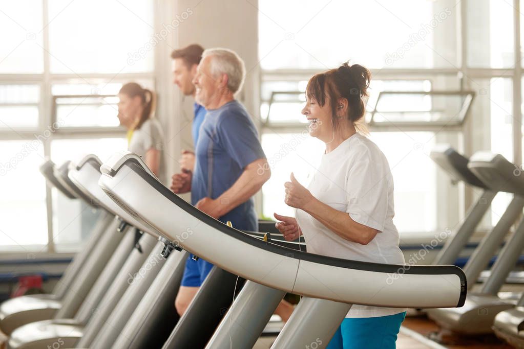 Mature caucasian woman running on treadmill.