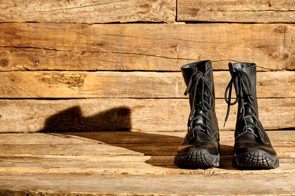 Zwarte gevechts legerlaarzen op hout. — Stockfoto