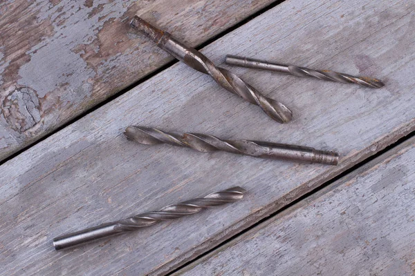 Rusty drill bits on wooden background.