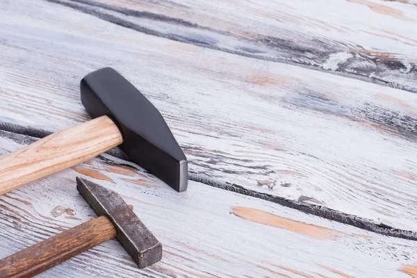Two different hammers on wooden background.