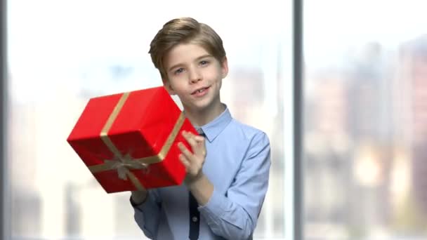 Мальчик трясет коробку с подарком . — стоковое видео