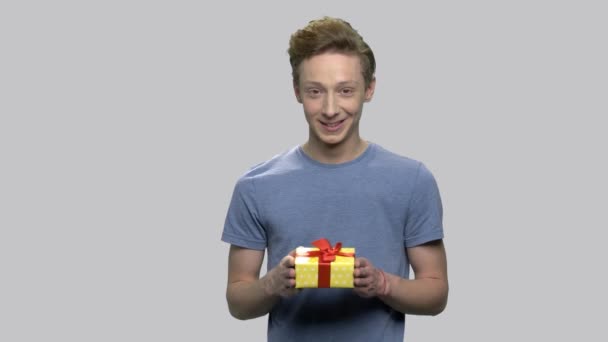 Leende teen pojke ger presentförpackning. — Stockvideo