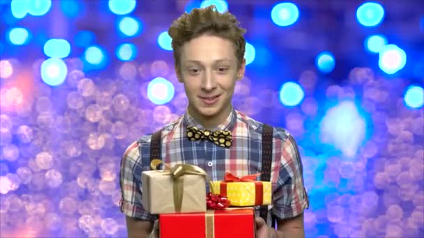 Expressieve tiener jongen met kerst geschenkdozen. — Stockvideo