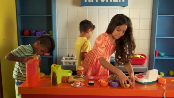 Діти грають з пластиковим посудом на іграшковій кухні . — стокове відео