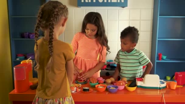 Niños jugando con la cocina de juguete en el jardín de infantes . — Vídeo de stock