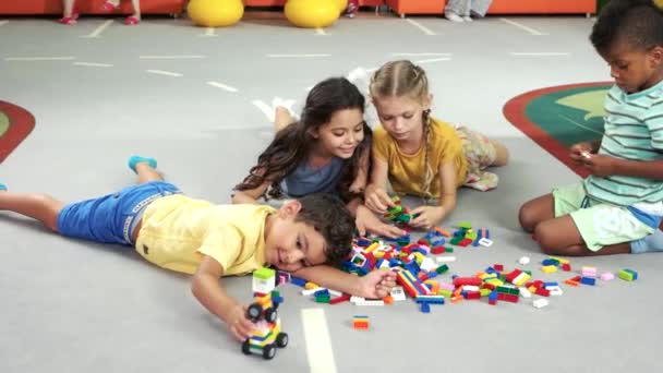 Смішні діти грають в барвисті іграшки в приміщенні . — стокове відео