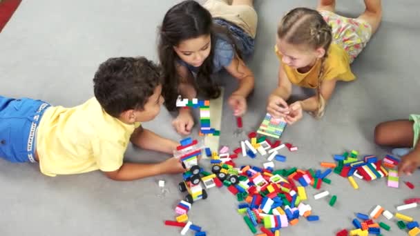 Kinder liegen auf dem Boden und spielen mit Spielzeug. — Stockvideo