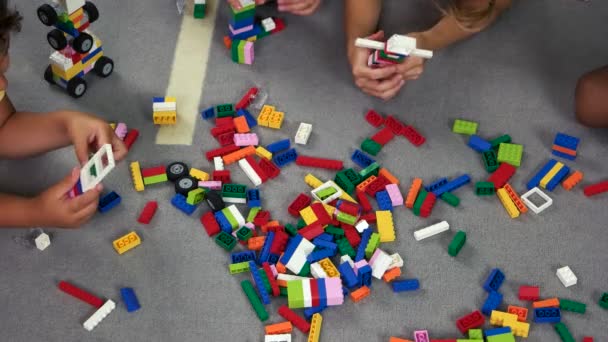 床の上でおもちゃのコンストラクターを再生する子供たちの手. — ストック動画