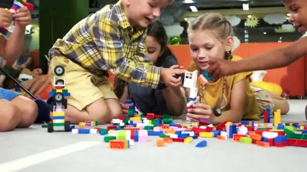 Kleine jongens en meisjesspelen met blok speelgoed in de speelkamer. — Stockvideo