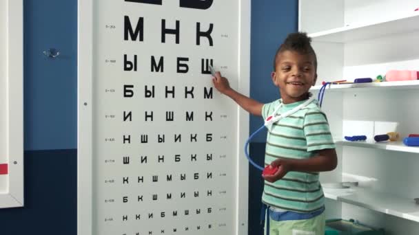 Kisfiú játszik orvos a Szemészek jel orvosi irodában. — Stock videók