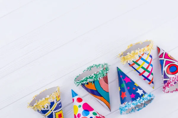 Variety of colored party hats on wooden background.