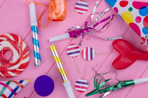 Birthday party accessories on pink wood.