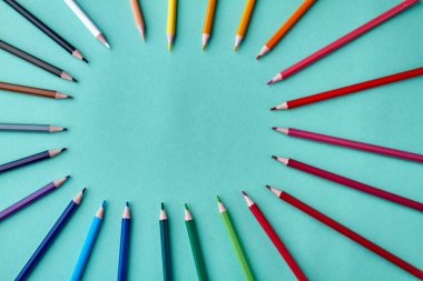 Turkuaz arka plan üzerinde renkli kalemlerden çerçeve.