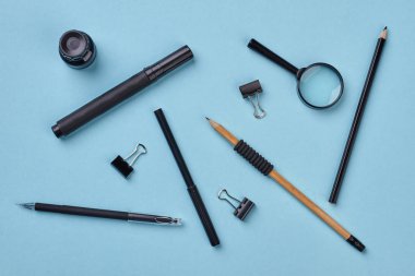 Mavi arka planda siyah okul malzemeleri.