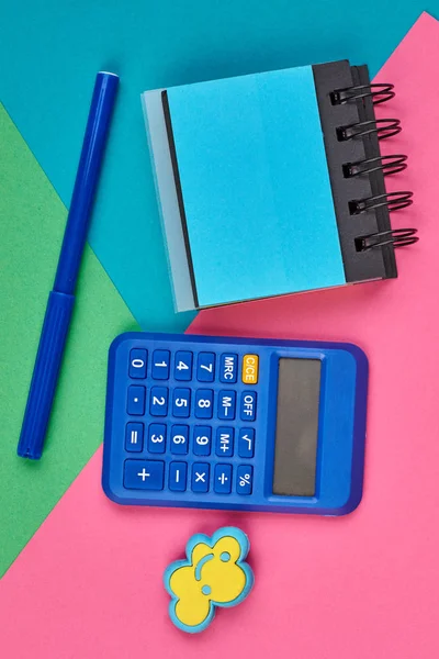 Calcolatrice, blocco note e pennarello sullo sfondo a colori . — Foto Stock