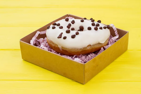 Donut in gift box on color background.