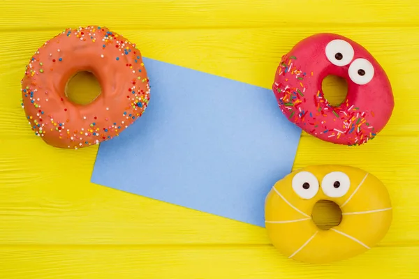 Três donuts e cartão de papel em branco . — Fotografia de Stock