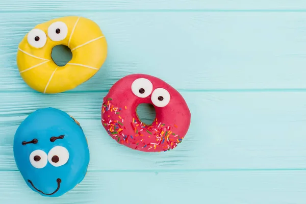 Três donuts engraçados no fundo pastel . — Fotografia de Stock