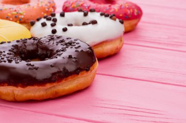 Pembe ahşap arka plan üzerinde lezzetli donuts.