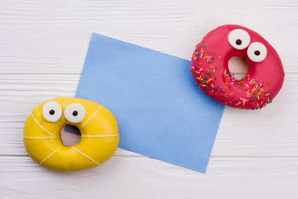 Dois donuts engraçados e cartão de papel em branco . — Fotografia de Stock