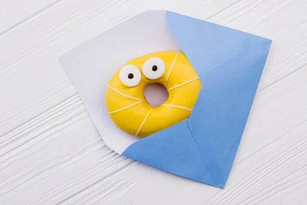 Envelope azul e rosquinha amarela . — Fotografia de Stock