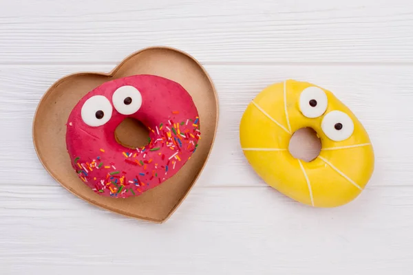 Donuts engraçados na mesa de madeira branca . — Fotografia de Stock