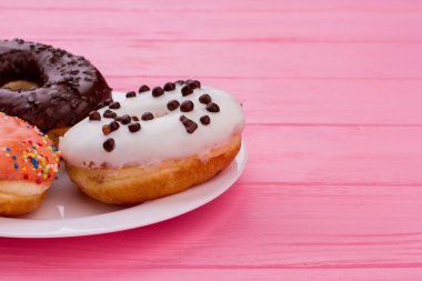 Pembe ahşap arka plan üzerinde çörekler ile Plaka.